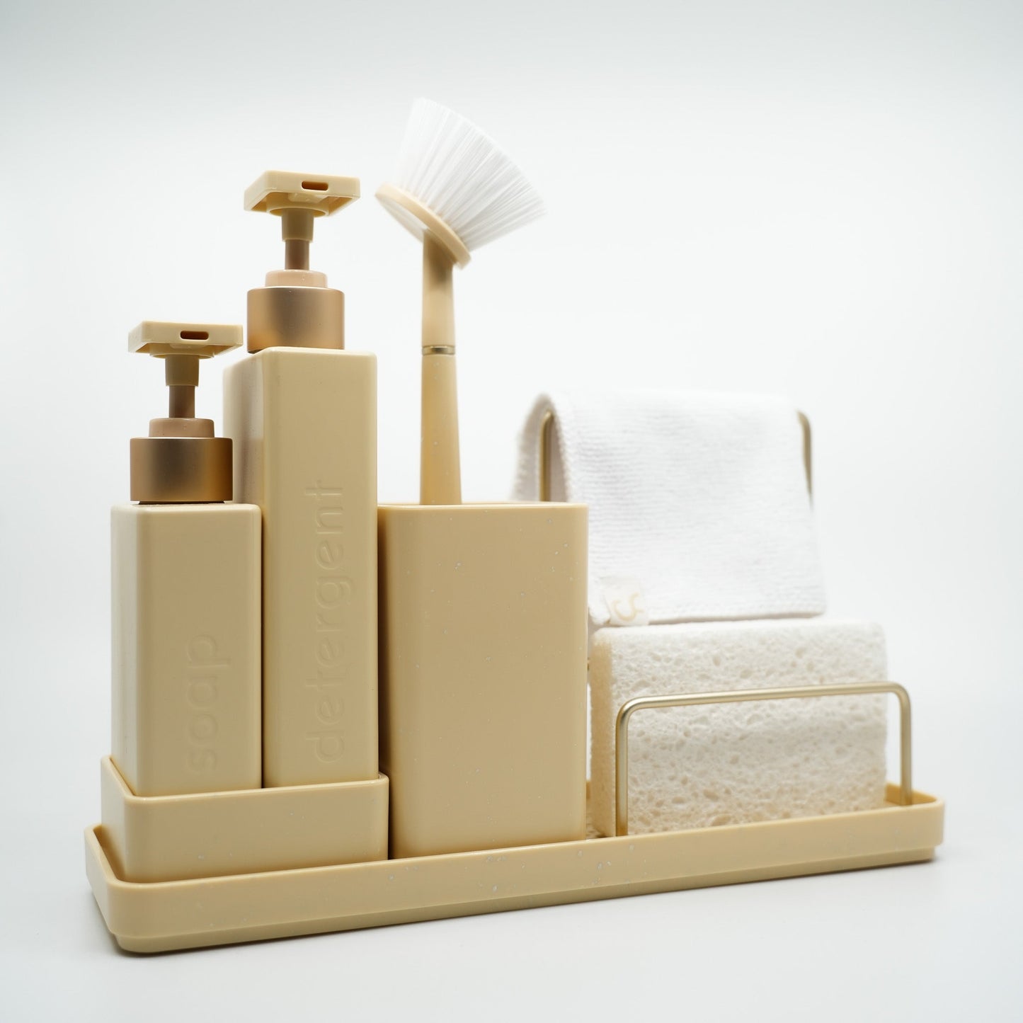 Beige bathroom accessory set with bottles, a brush, and towels on a white background