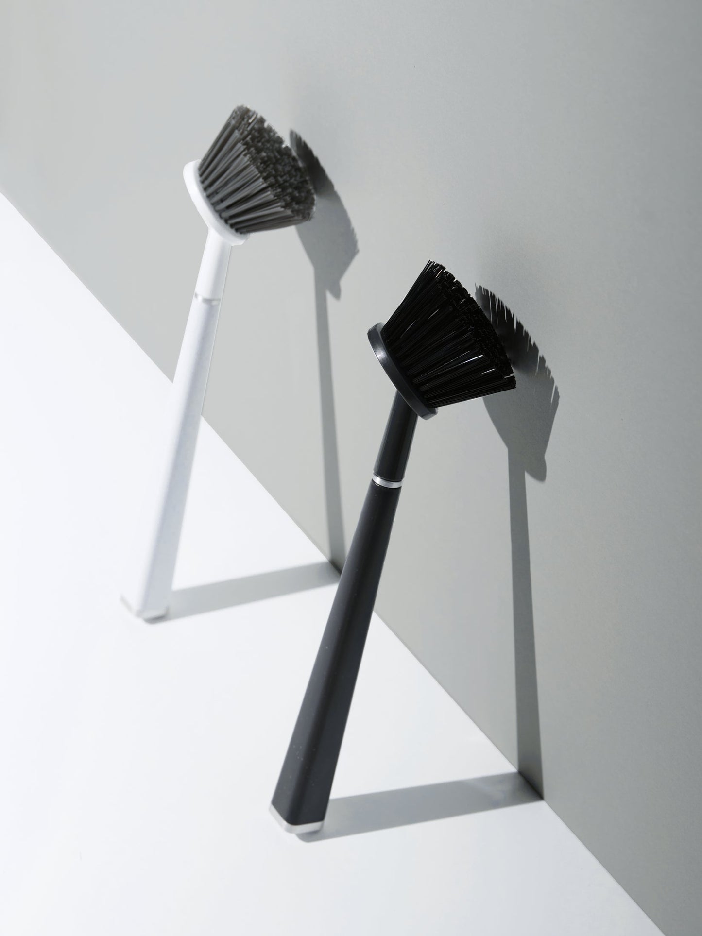 Two cleaning brushes with black bristles on white and gray background