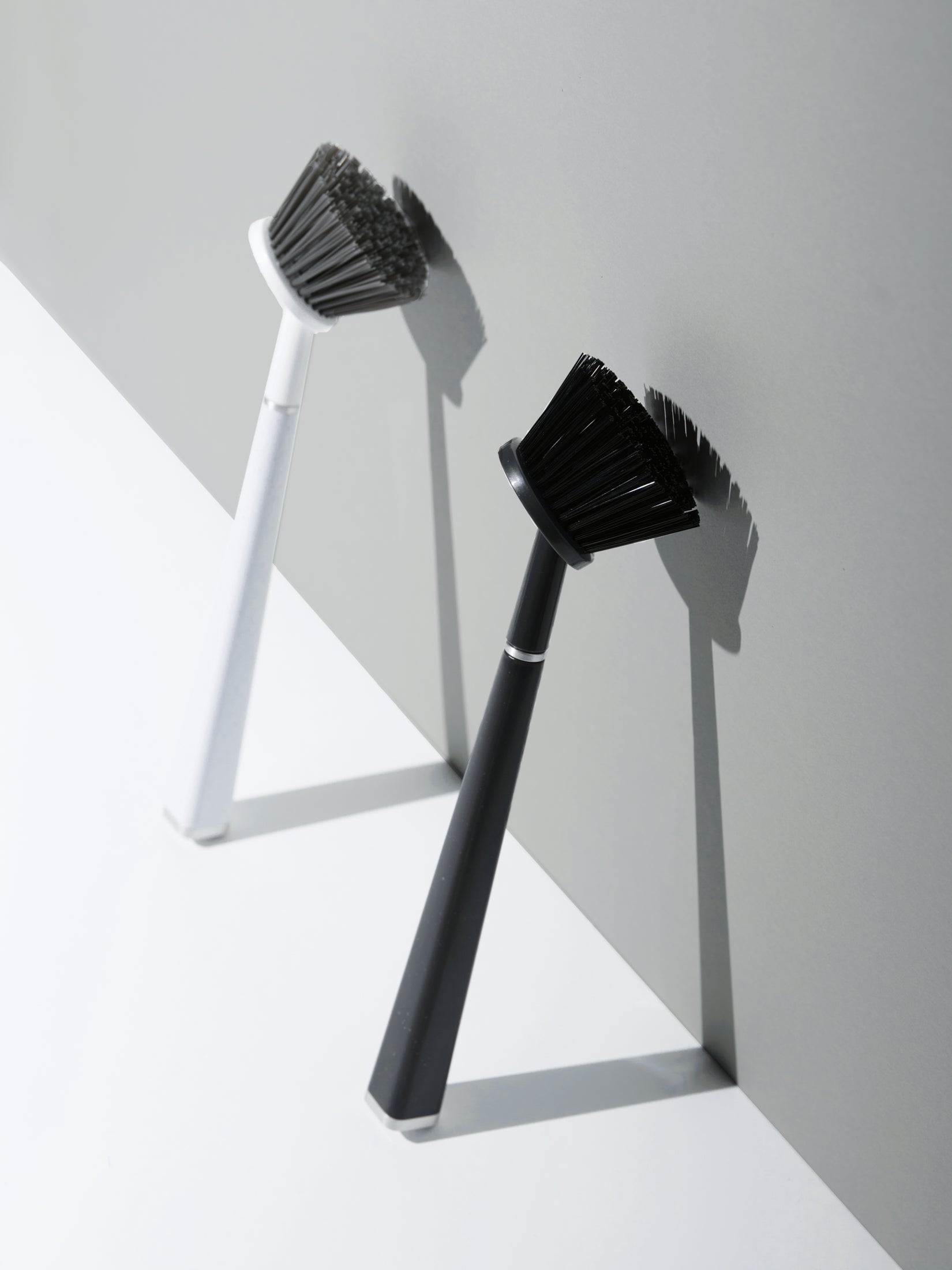 Two cleaning brushes with black bristles on white and gray background